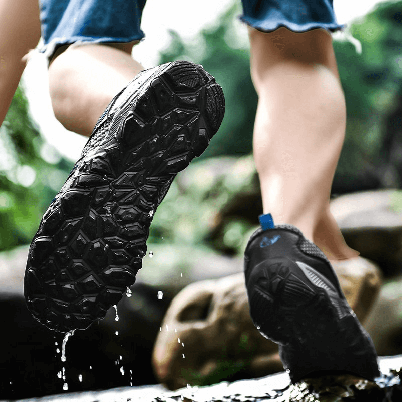 Person running with stylish mesh breathable sneakers SF0752 showing anti-slip sole in action over wet rocks.