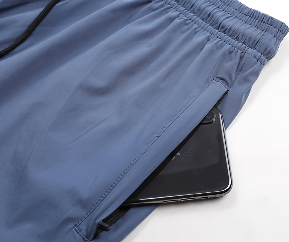 Stylish quick-drying sporty men's pants with cuffs, showcasing a secure zippered pocket holding a smartphone for training convenience.