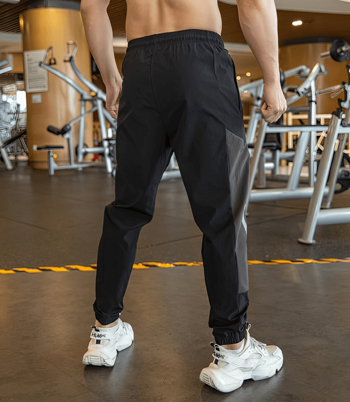 Back view of stylish quick-drying sporty men's pants with cuffs ideal for running, in a gym setting.