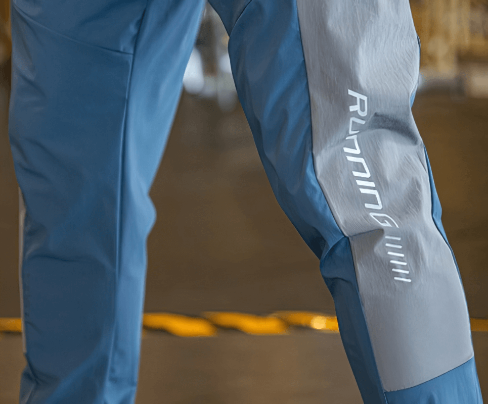 Close-up of stylish quick-drying blue men's sporty pants with cuffs for running, showcasing flexible material and sleek design.