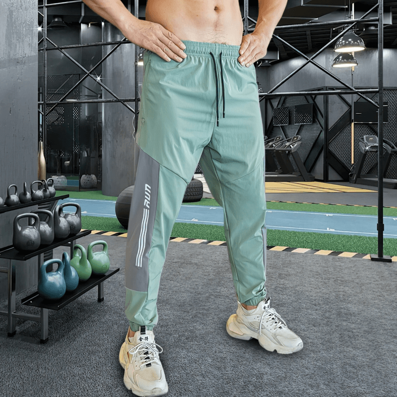 Stylish quick-drying sporty men's pants with cuffs for running, showcasing flexibility and comfort in a sleek gym setting.