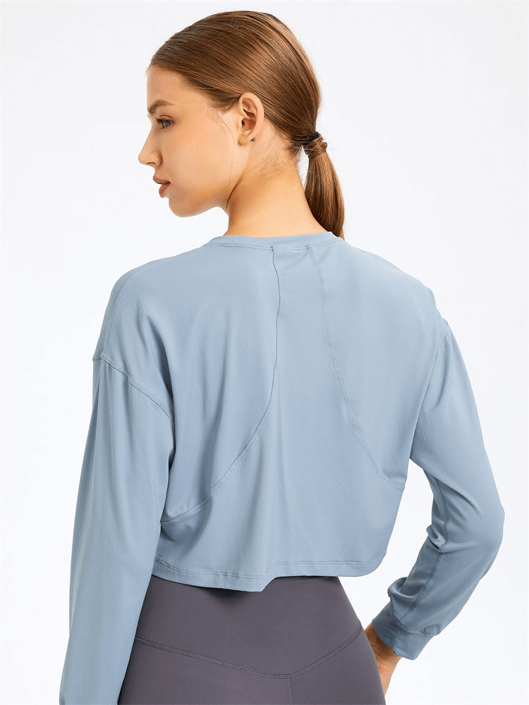 Woman wearing a stylish sport short women's sweatshirt with long sleeves and breathable spandex, ideal for yoga sessions.