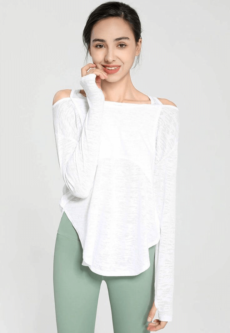 Woman wearing a stylish lightweight white top with long sleeves and shoulder cutouts, ideal for yoga and active lifestyle.