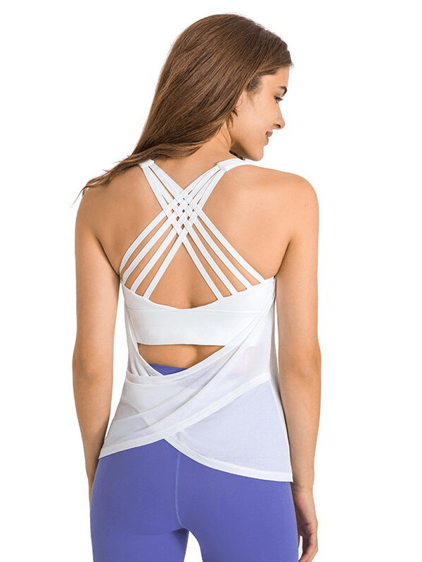 Woman wearing a stylish sporty white top with open back and cross straps, perfect for yoga and fitness, over blue leggings.