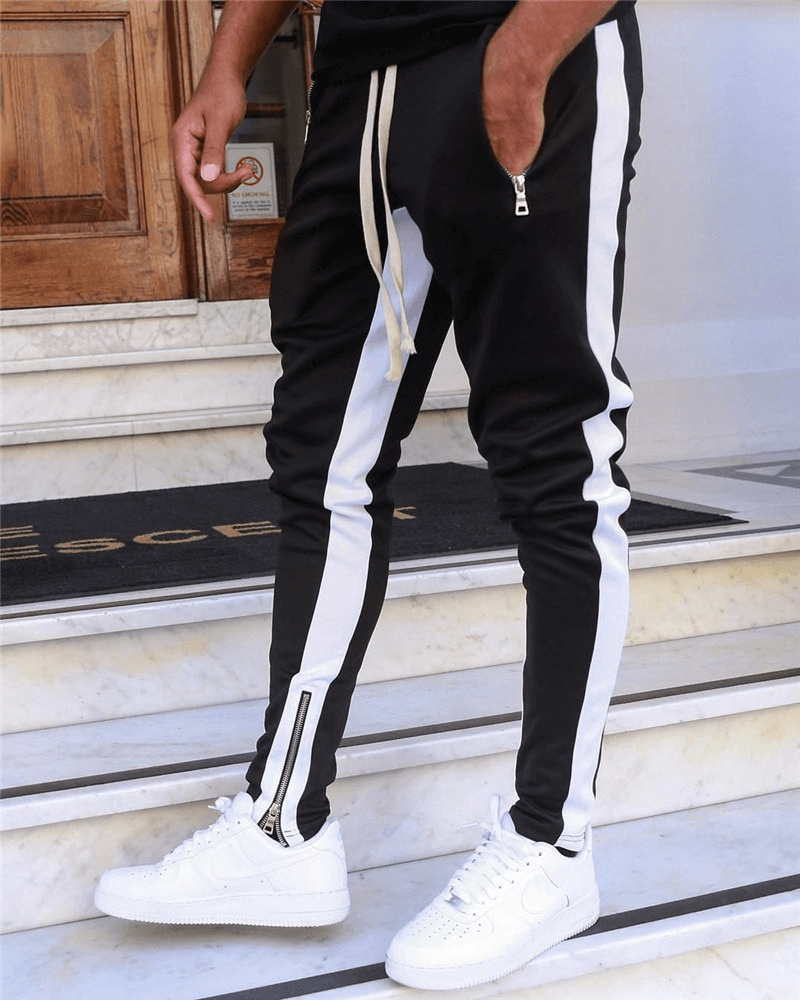 Stylish two-tone sports jogging pants for men with zipper pockets, perfect for running, shown on stairs.