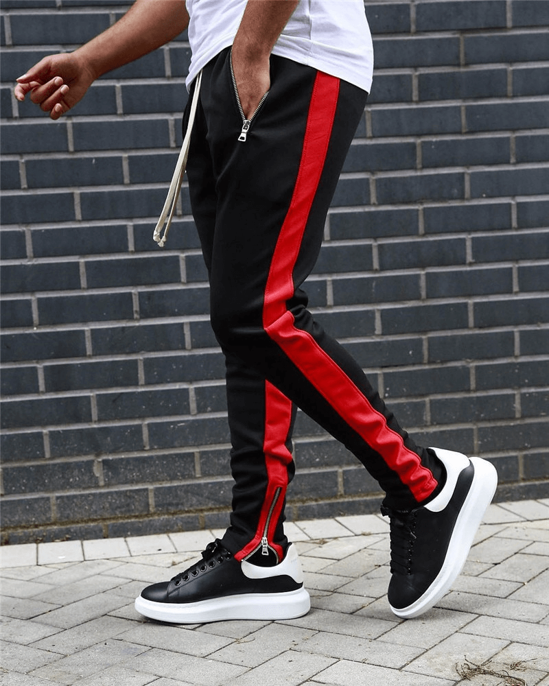 Man wearing stylish two-tone sports jogging pants with zipper pockets, featuring black and red stripes, perfect for running.