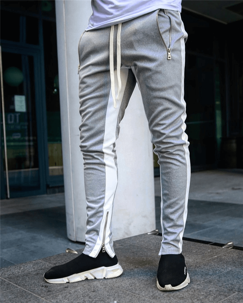 Men's stylish two-tone jogging pants in gray with zipper pockets, drawstring, and sleek sneakers
