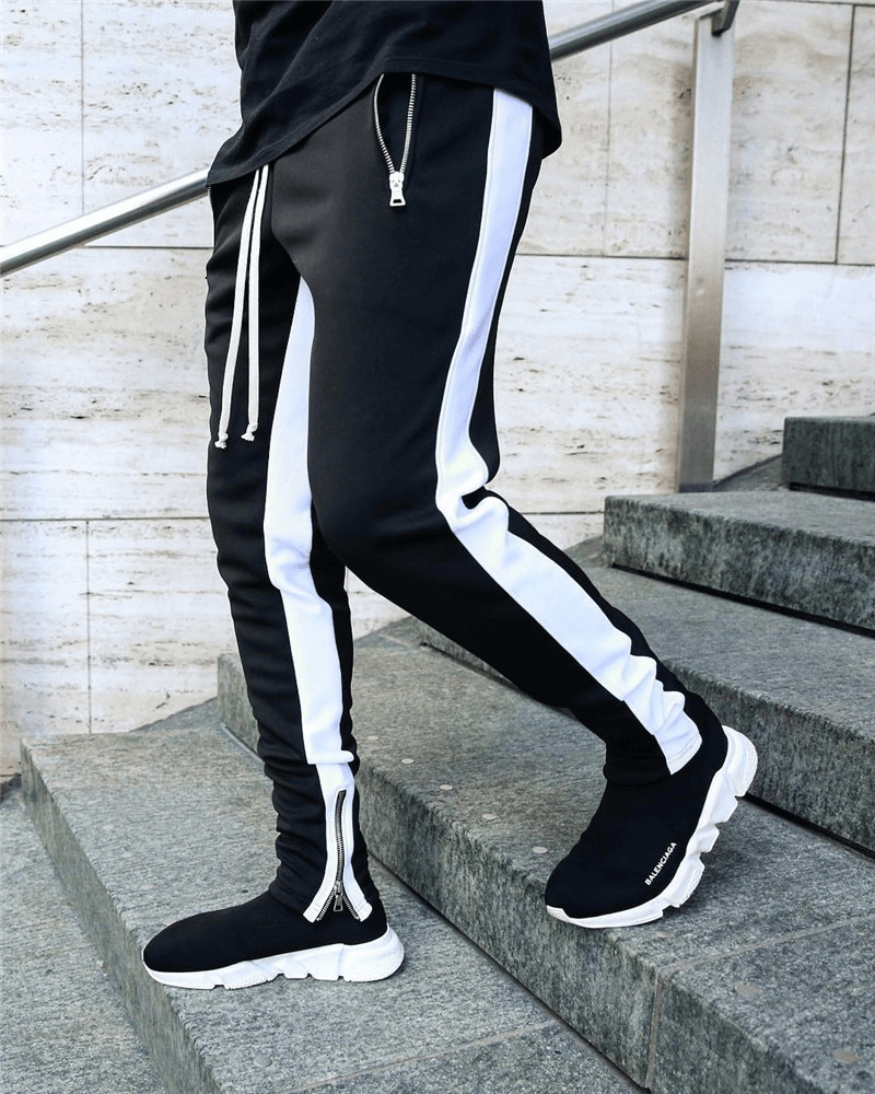 Man wearing stylish two-tone jogging pants with zipper pockets, showcasing comfort and style on the steps.