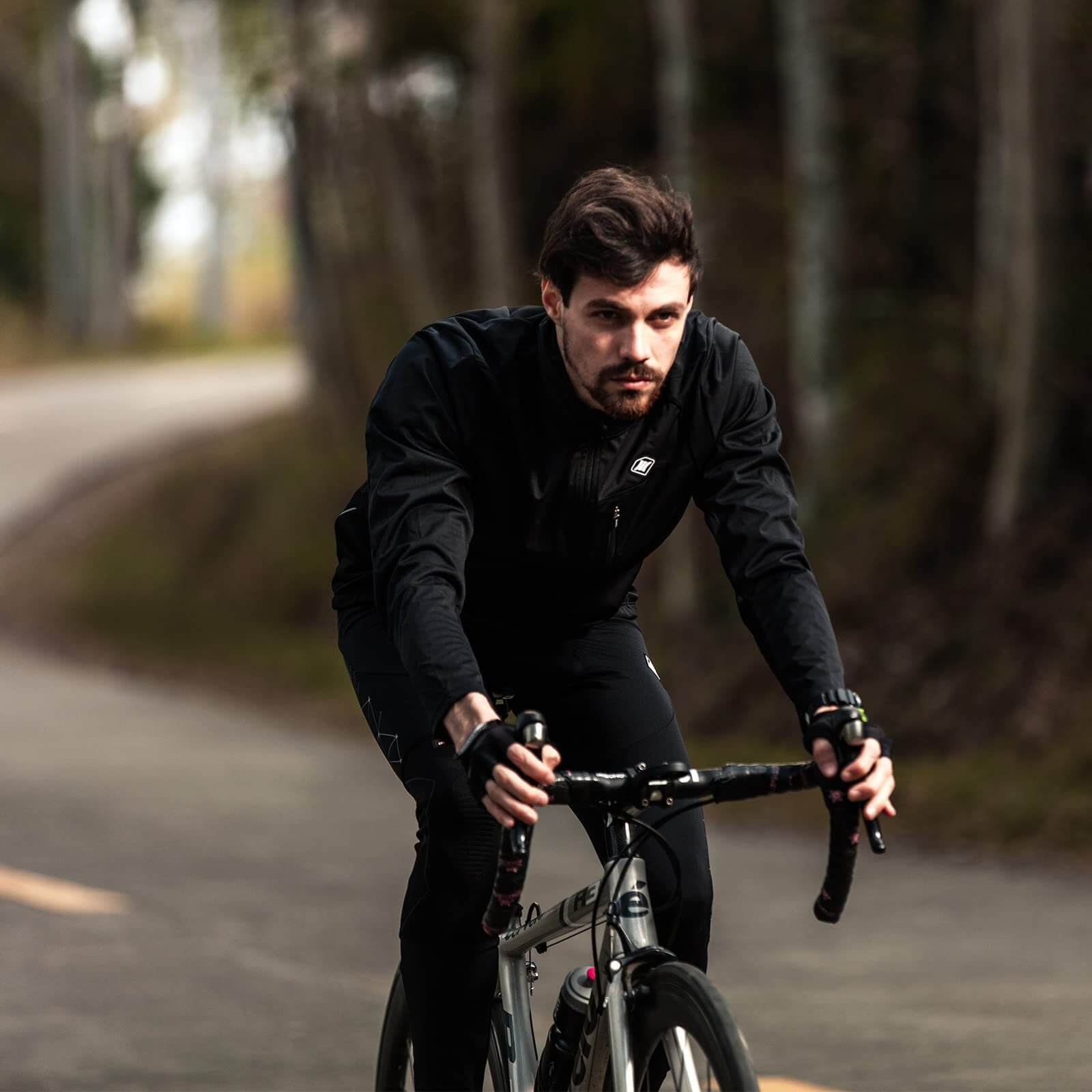 Man cycling on road wearing stylish warm bike jacket with high slit pockets, showcasing windproof breathable comfort.