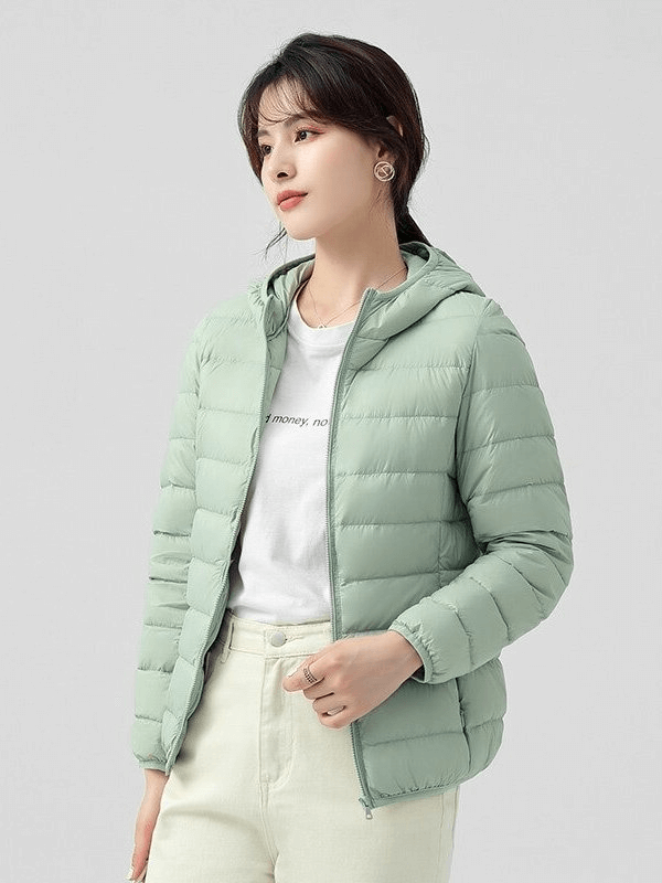 Woman wearing a stylish green down jacket with hood, perfect for warmth and comfort in winter outdoor activities.