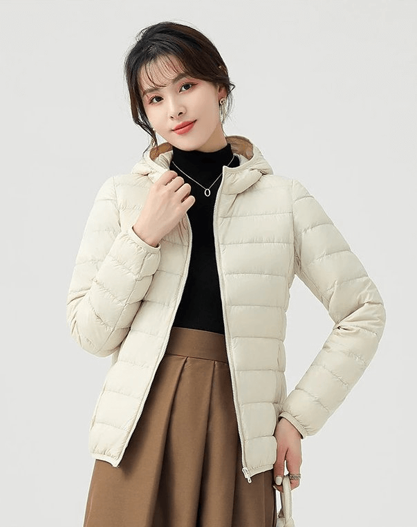 Woman wearing a stylish beige down jacket with hood, made from lightweight nylon, perfect for outdoor activities with windproof and waterproof features.