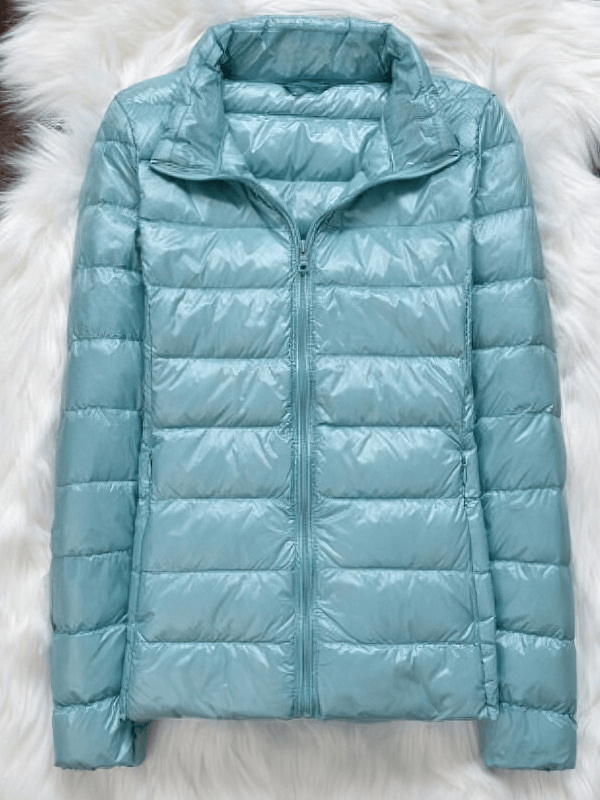 Stylish women's down jacket without hood, light blue with full sleeves and zipper closure, on a fluffy white background.