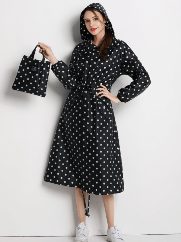 Woman modeling stylish polka-dot waterproof raincoat, holding matching bag, perfect for outdoor activities and rainy days.