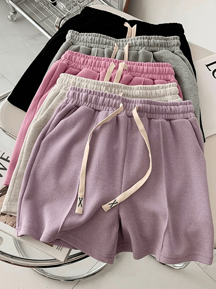 Collection of stylish women's high-waist shorts with side pockets in various solid colors, featuring an elastic waist.