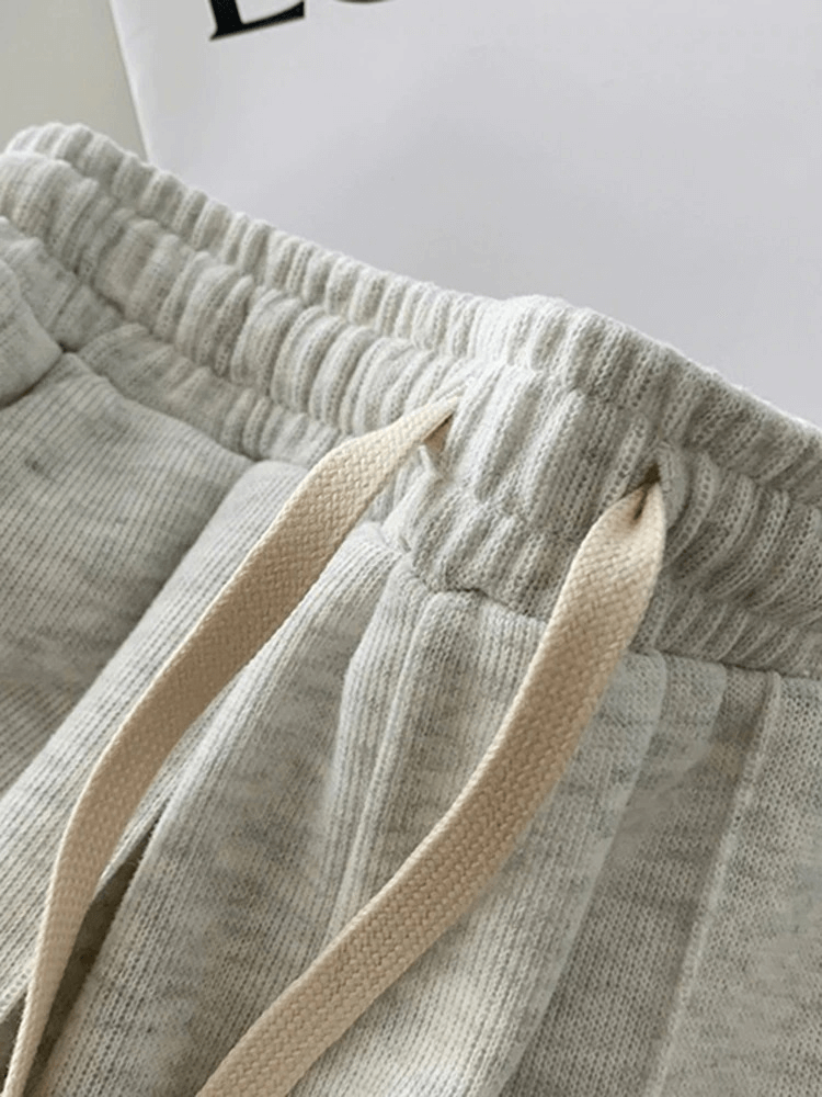 Close-up of women's high-waist shorts with elastic band and drawstring in grey, featuring a textured fabric and stylish design.