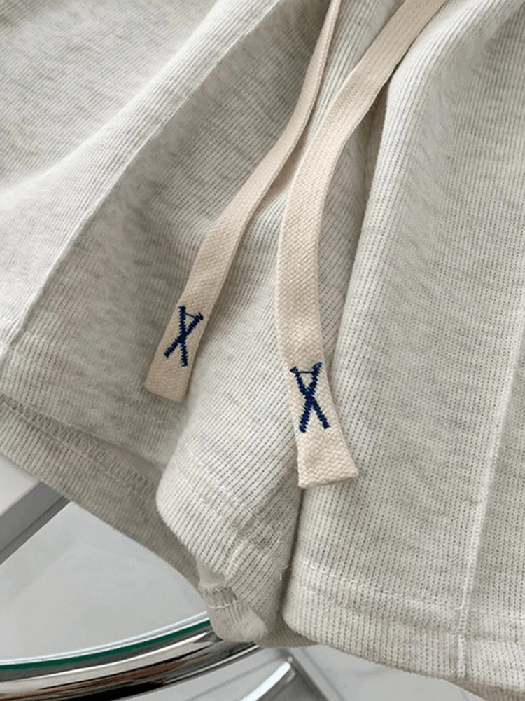 Stylish high-waist women's shorts in premium cotton with side pockets and drawstrings featuring embroidered X details.