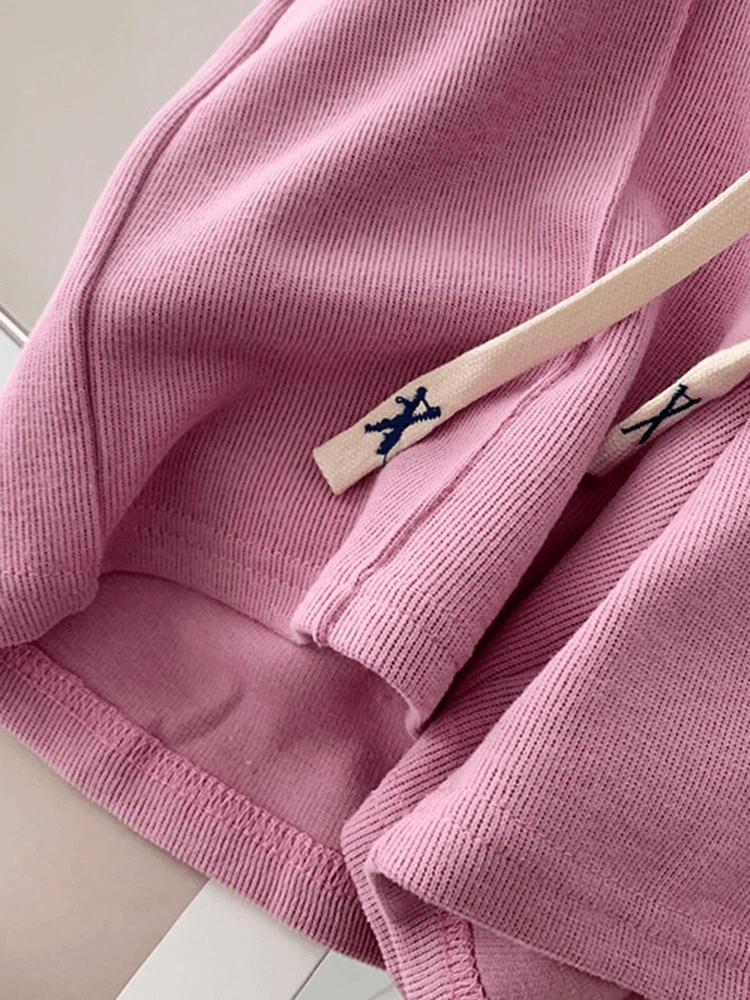 Close-up of pink high-waisted women's shorts with side pockets and drawstring detail for a casual look.