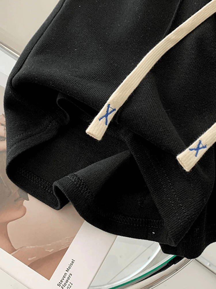 Close-up of black high waist women's shorts with side pockets and white drawstring, perfect for casual style.