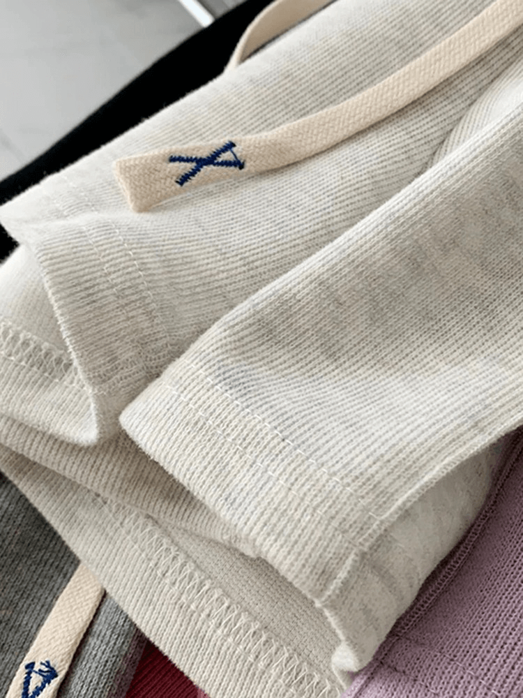 Close-up of folded knit fabrics in beige, grey, and pink, showcasing texture and craftsmanship.