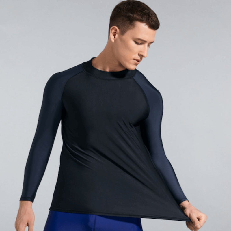 Men's elastic compression shirt for swimming and sports, offering sun protection and UV coverage, modeled by a man stretching the fabric.