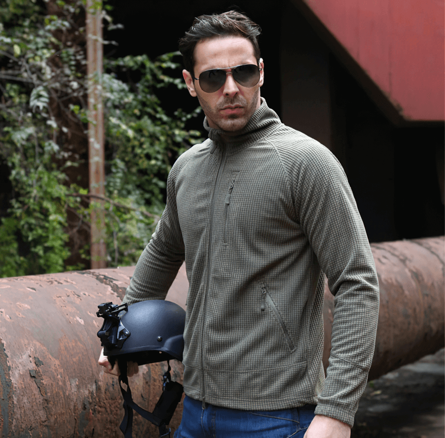 Man wearing Tactical Lightweight Fleece Jacket in Army Green, holding a helmet, showcasing warm and stylish military-inspired clothing.