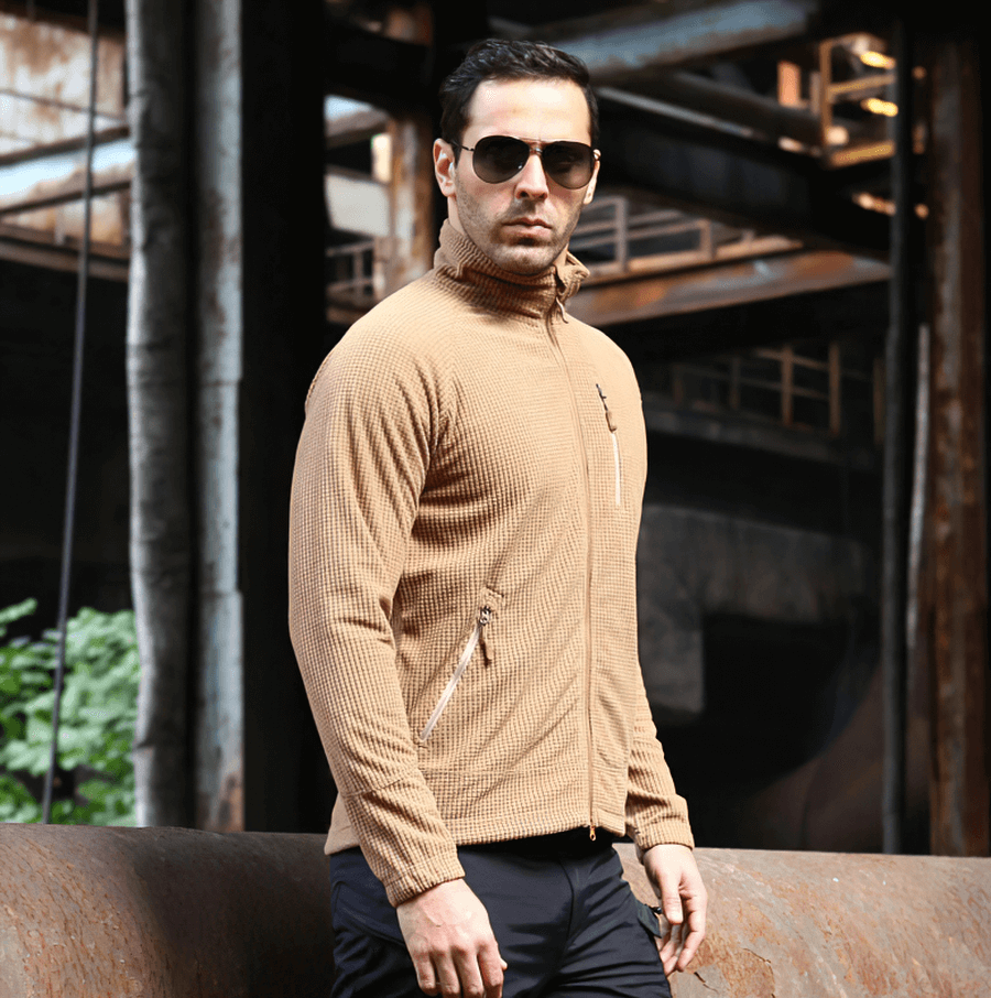 Man wearing tactical lightweight fleece jacket in khaki color, perfect for warmth and style in outdoor settings.