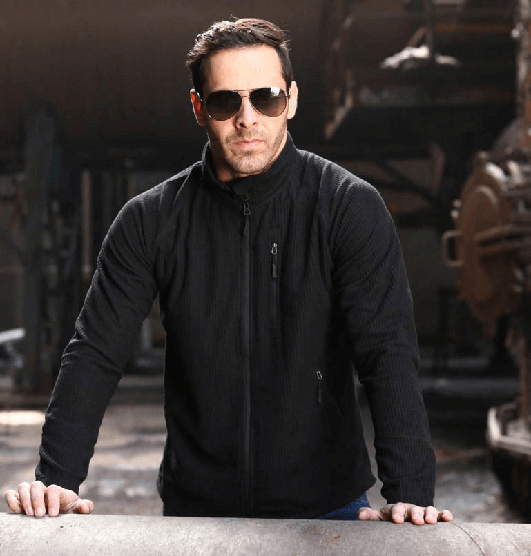 Man wearing black tactical lightweight fleece jacket in industrial setting.