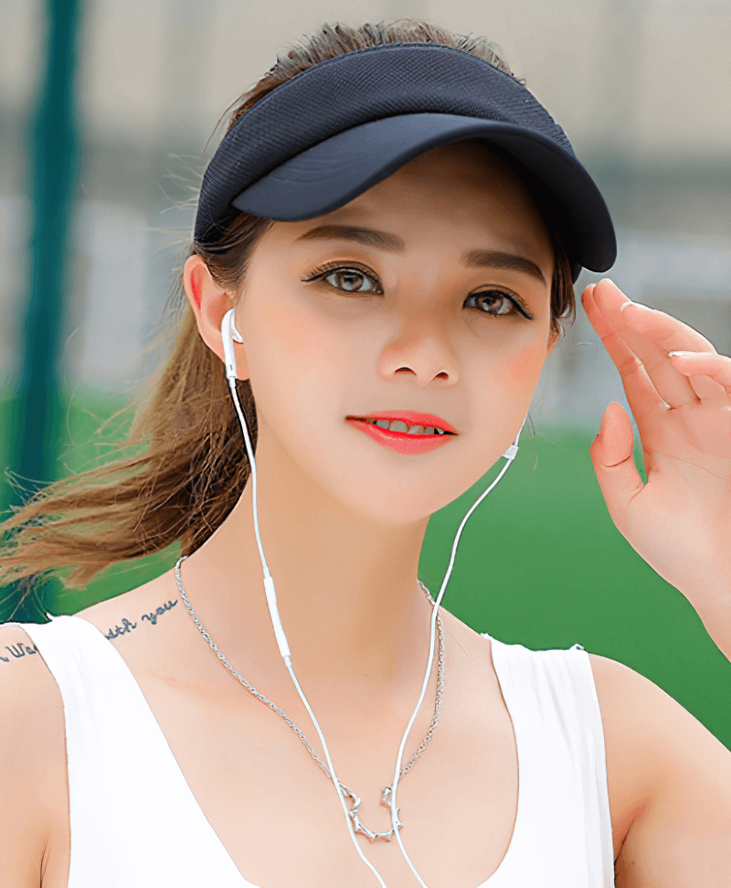 Woman wearing a Tennis Golf Breathable UV Protection Adjustable Visor Cap while listening to music outdoors.