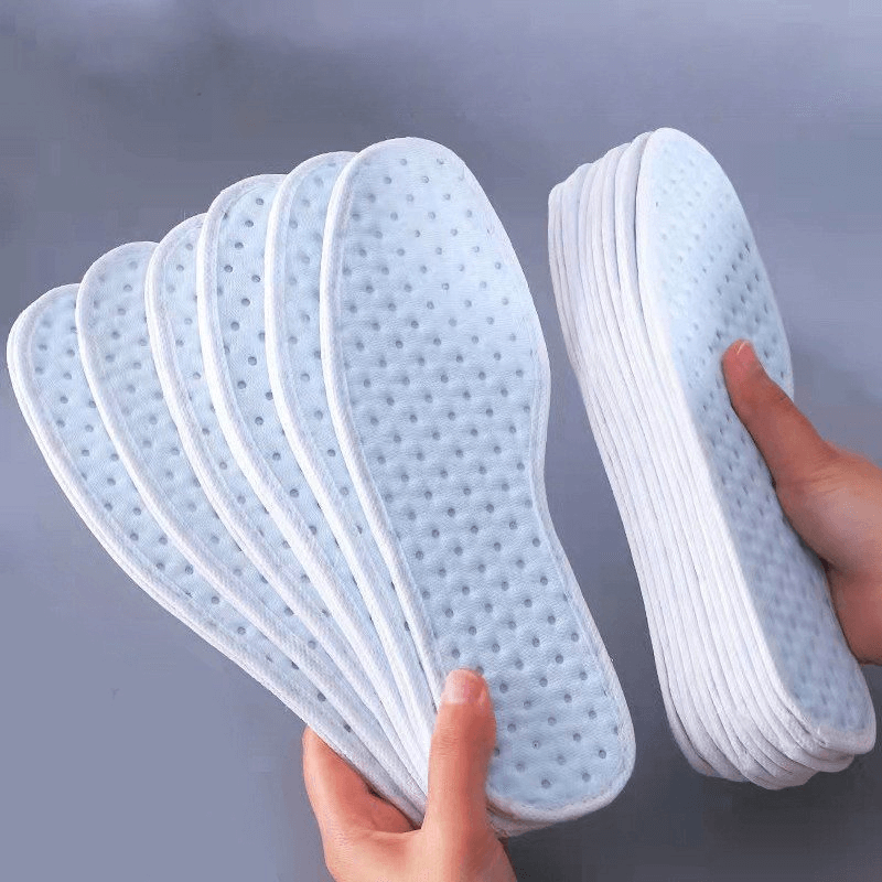 Hands holding multiple antibacterial shock absorbing insoles for sports shoes, showcasing their thickness, light weight, and durability.