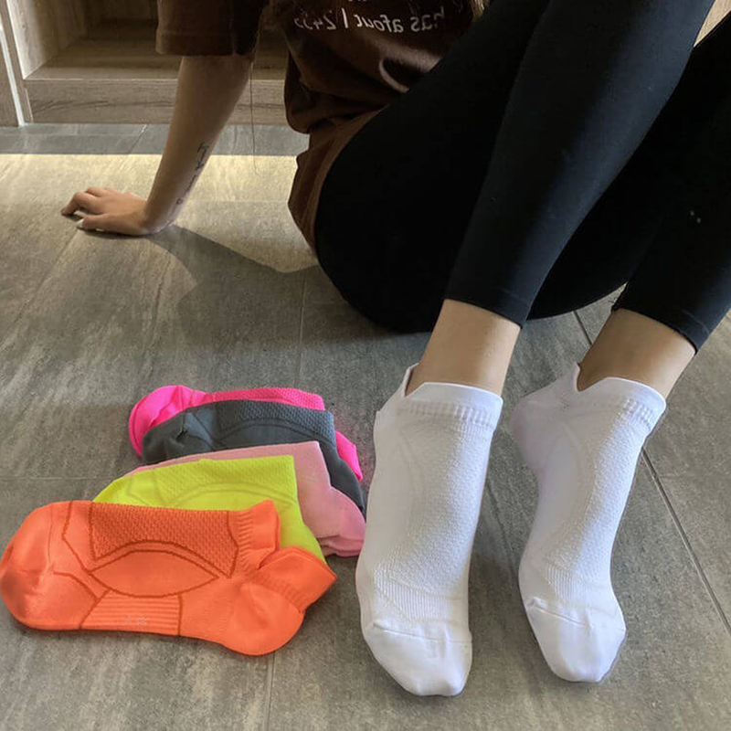Unisex thin anti-slip breathable sports socks in various colors, ideal for running. Socks displayed on person's feet and floor.