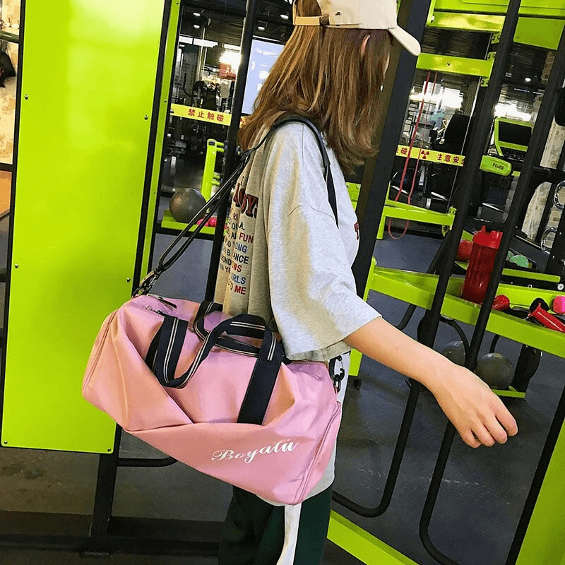 Woman carrying pink waterproof crossbody gym bag with specialized pockets, perfect for active lifestyles and outdoor sports.