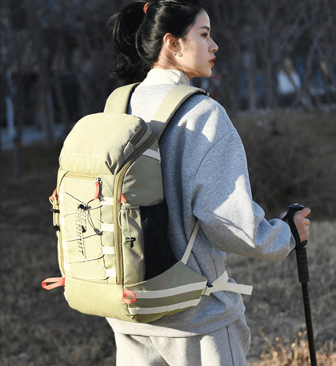 Person hiking outdoors with a 40L travel backpack in green, featuring a rain cover and a comfortable fit for adventure.