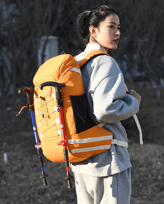 Person wearing orange travel backpack with hiking poles, perfect for outdoor sports and travel, 40L capacity, unisex design, practical style.