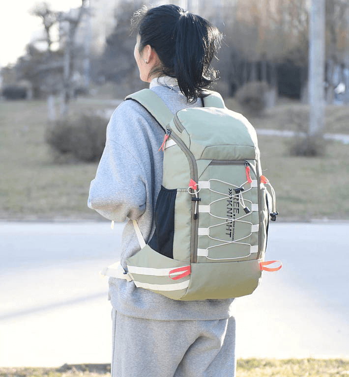 Person wearing green travel backpack 40L with rain cover outdoors, ideal for sports and adventure. Model SF0330, stylish and practical.