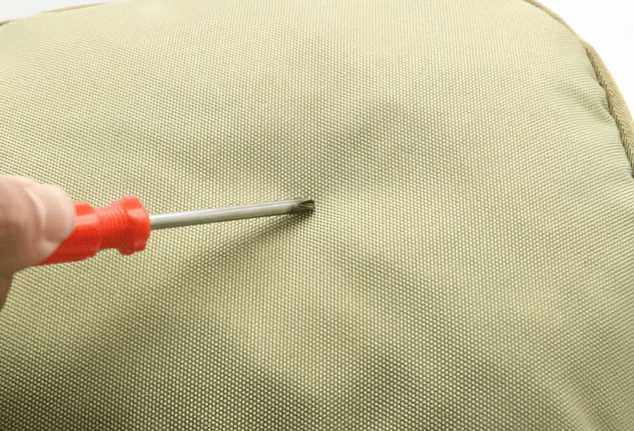 Close-up of waterproof Jacquard fabric on a 40L travel backpack, showcasing durability with a screwdriver test.