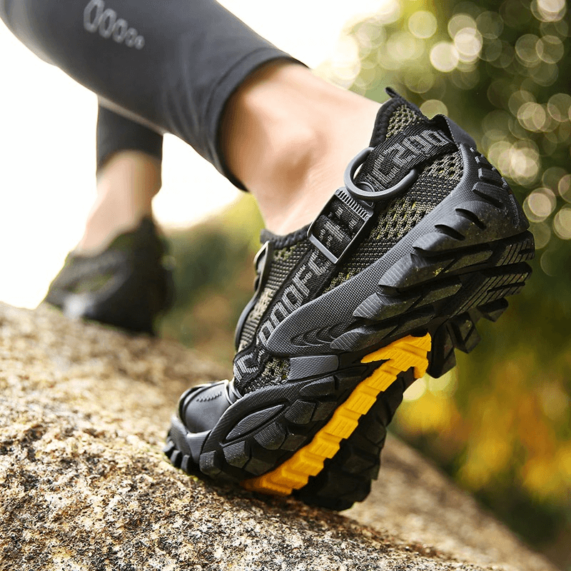 Close-up of Trekking Flexible Hiking Boots, showcasing rugged design and breathable fabric on rocky terrain.