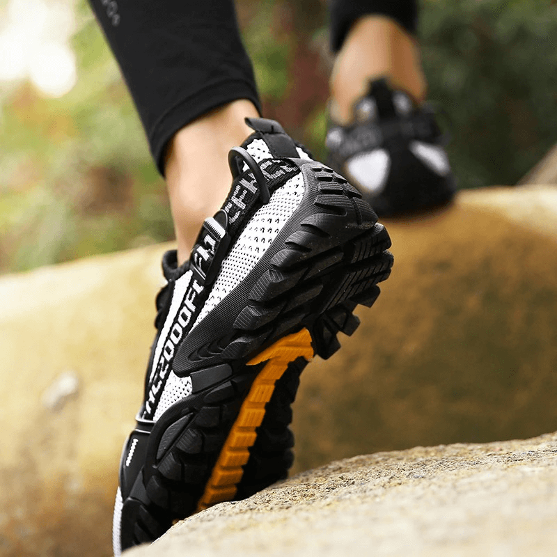 Close-up of Trekking Flexible Hiking Boots on rocky terrain, showcasing breathable design and rubber soles for comfort and performance.