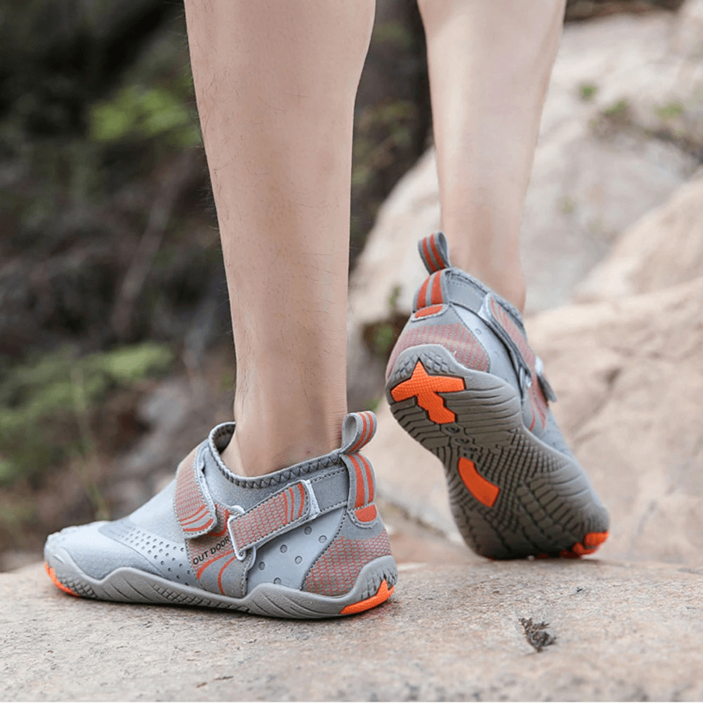 Person wearing gray and orange unisex breathable nonslip aquatic sneakers for swimming, featuring rubber outsole and hook & loop closure.
