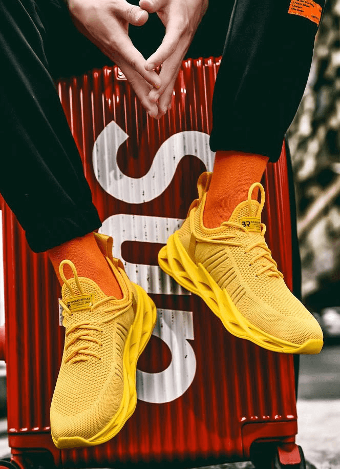Yellow unisex mesh breathable running shoes with lace-up style, displayed against a red suitcase with bold white text.