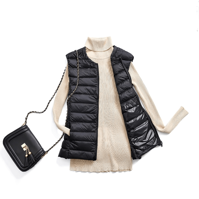 Black ultra-light women's vest with pockets over a beige sweater, paired with a trendy black purse. Cozy and stylish outwear fashion.