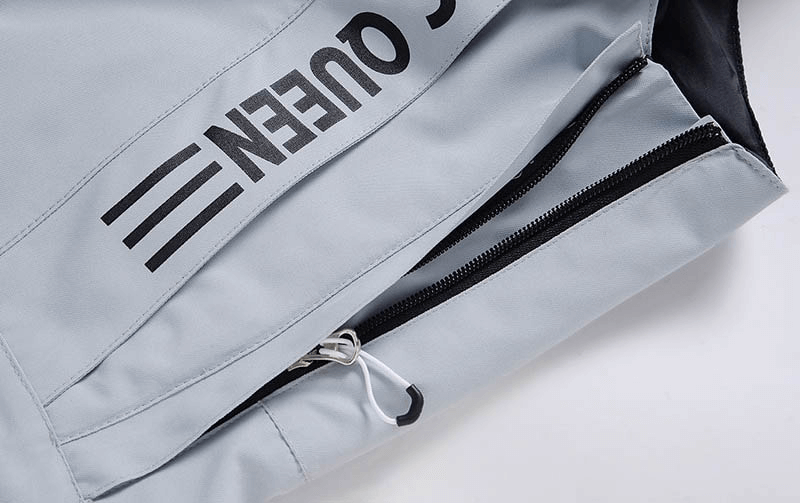 Close-up of waterproof zipper detail on grey snowboarding pants from Queen collection, featuring strap and polyester material.