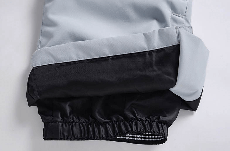 Close-up of warm waterproof zipper strap snowboarding pants in light gray with black cuff detailing, perfect for winter skiing.