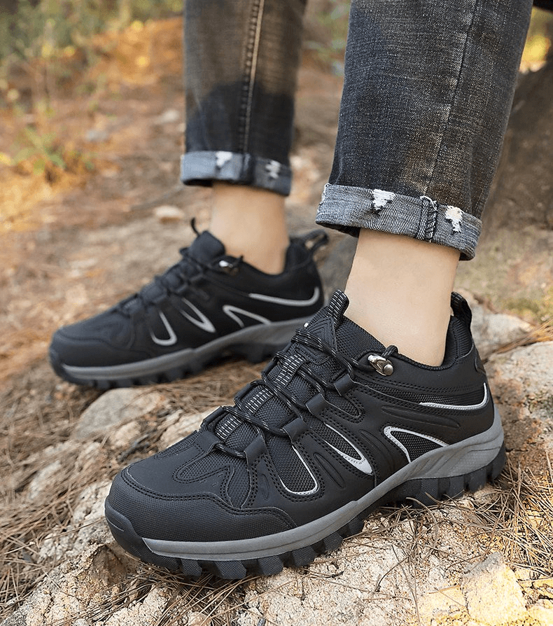 Man wearing Waterproof Anti-Slip Trekking Shoes SF0753, showcasing durable rubber outsole on rocky terrain.