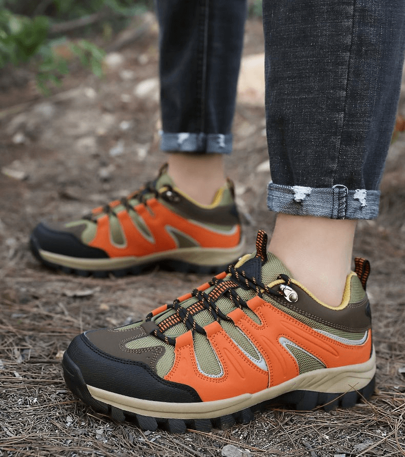 Person wearing waterproof anti-slip trekking shoes with orange and brown design, ideal for men's outdoor adventures and hiking.