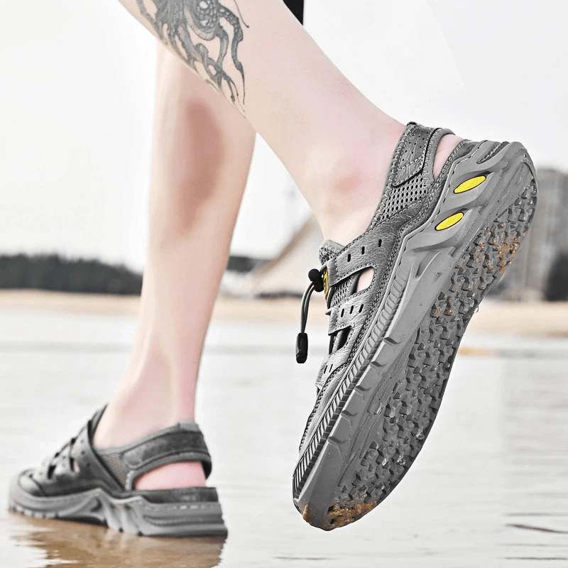 Person wearing gray hollow-out breathable mesh sandals with wear-resistant PVC outsole; perfect for outdoor adventures.