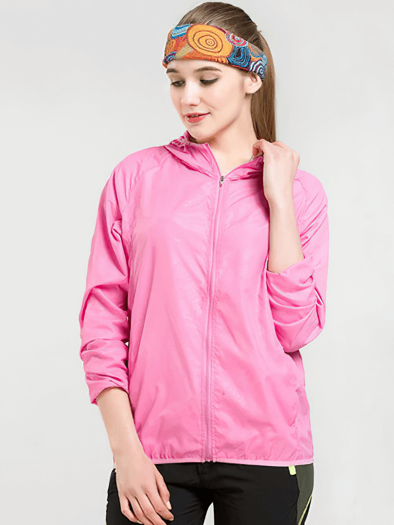 Woman wearing a pink waterproof hooded jacket with pockets, designed for outdoor activities like hiking and camping. Unisex style.