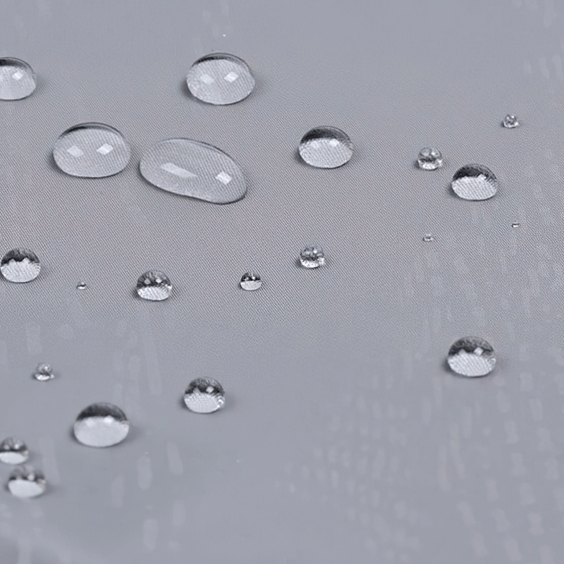 Close-up of water droplets on a grey waterproof jacket showcasing its water-resistant fabric.