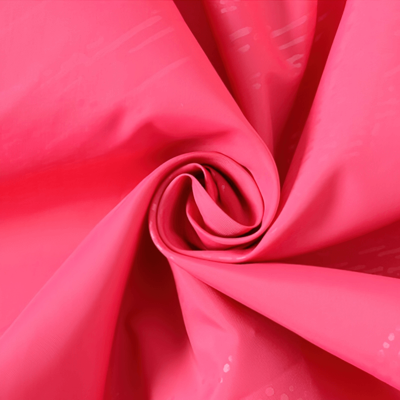 Close-up of pink waterproof nylon fabric used in unisex jackets for outdoor activities.