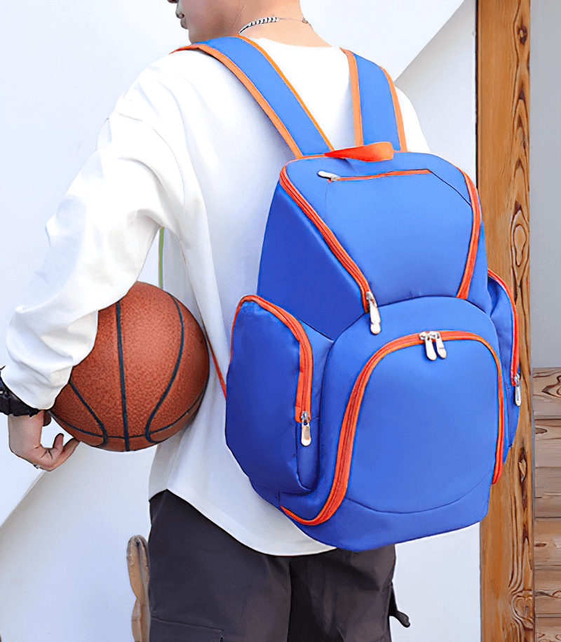 Person wearing a waterproof lightweight large capacity football backpack in blue, holding a basketball.