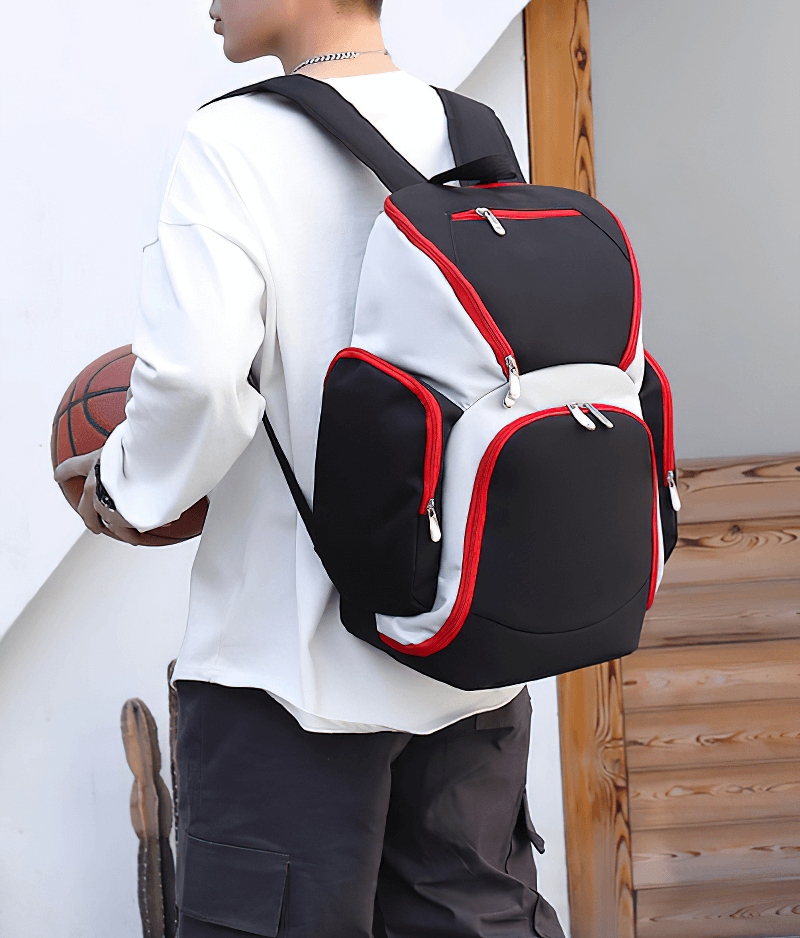 Man carries waterproof lightweight football backpack with large capacity, showcasing durable nylon design with red accents.